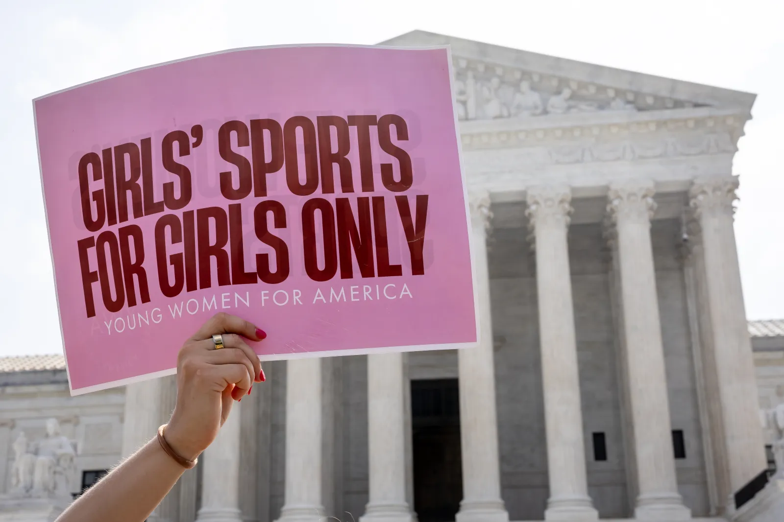 A person holds a sign advocating for a ban on transgender women and girls participating in women's and girls' sports outside the U.S. Supreme Court building as the court announced decisions in Washington, D.C., on June 29, 2026.