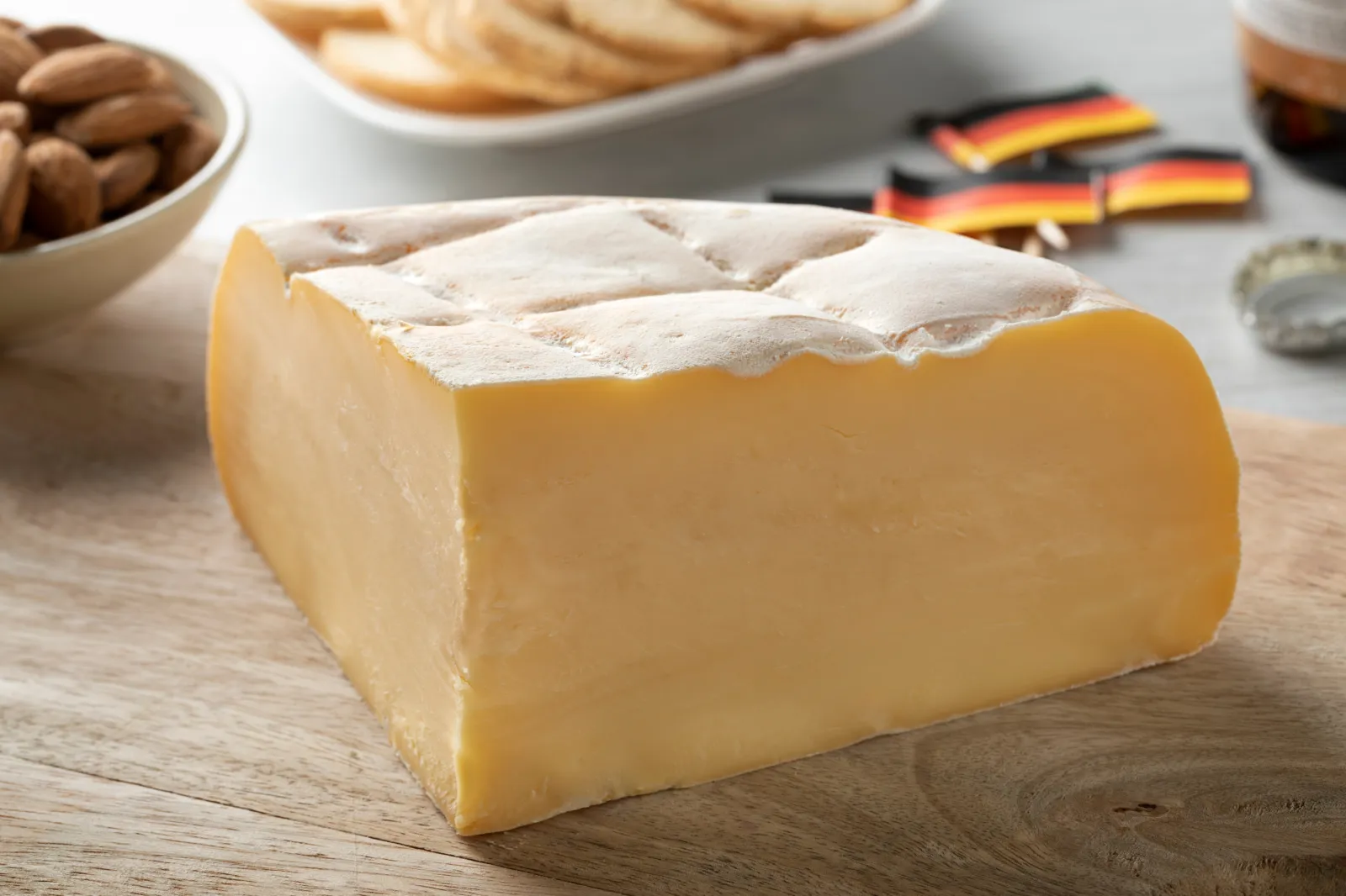 A soft Belgian cheese, similar to Cabricharme, is pictured on a wooden cutting board.