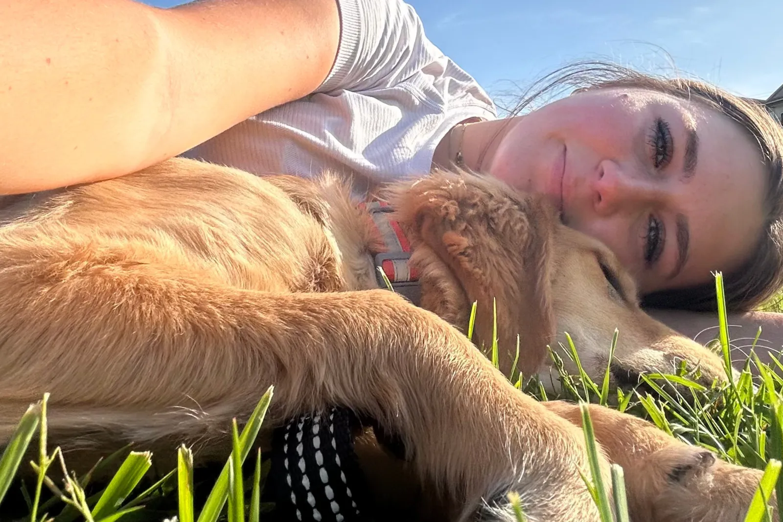 Elana lying on the grass with her rescue dog called Ollie.