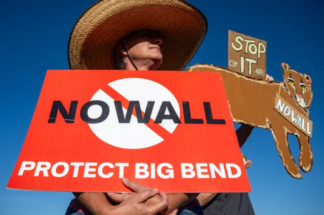 A woman hold's a sign to protest the plans by US President Donald Trump's administration to build a section of the border wall at the Big Bend National Park in Study Butte, Texas, on August 15, 2026.