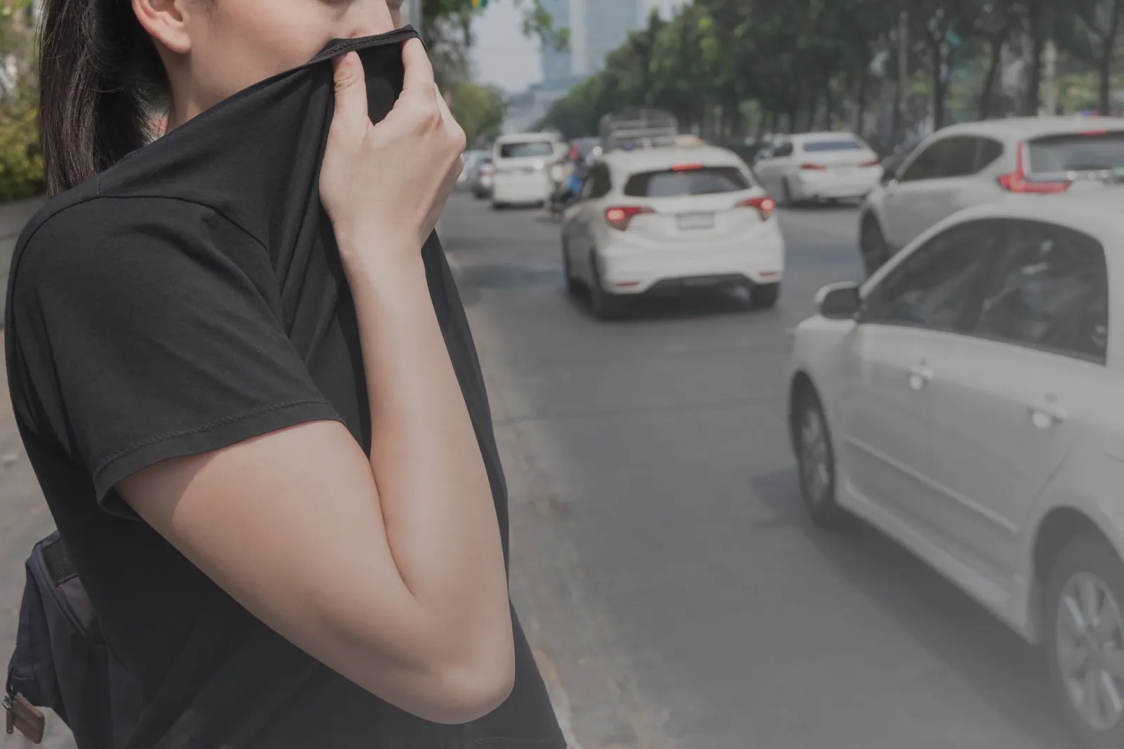 A stock image shows a woman covering her nose with her hand because of bad traffic pollution.