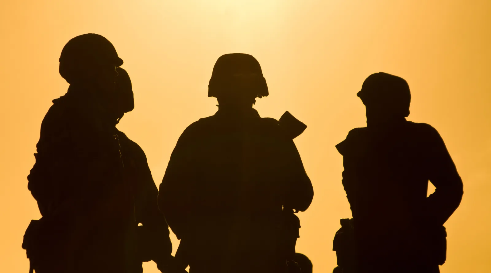 Soldiers standing against sunset abstract background.