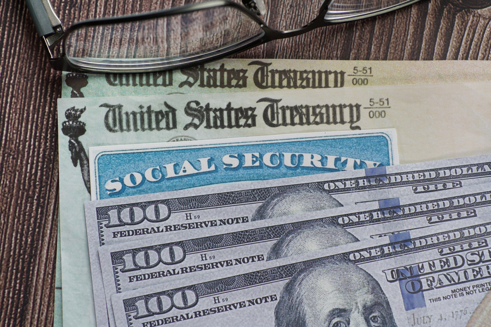 Stock image: a Social Security card lies with U.S. dollar bills and Treasury checks.
