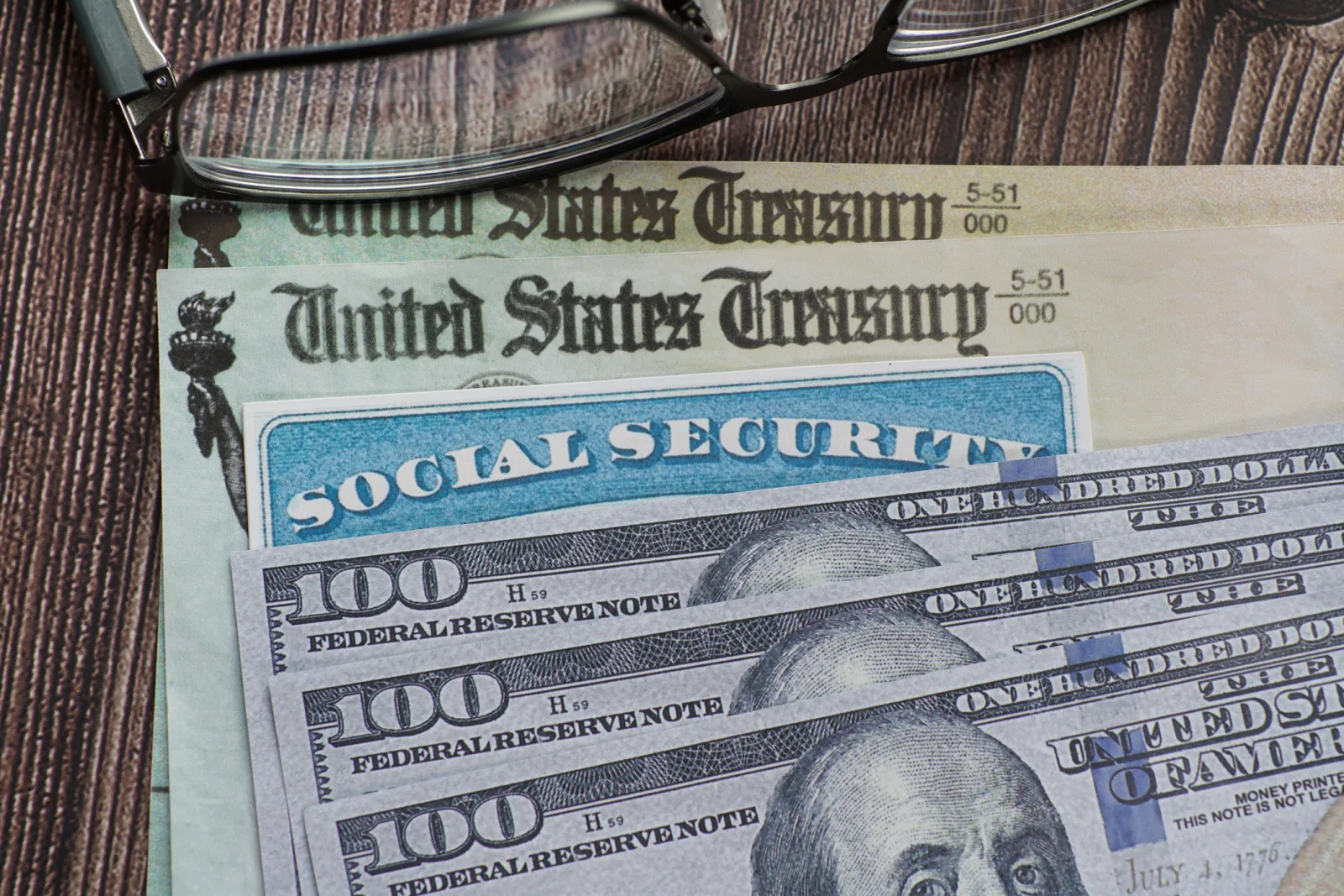 Stock image: a Social Security card lies with U.S. dollar bills and Treasury checks.