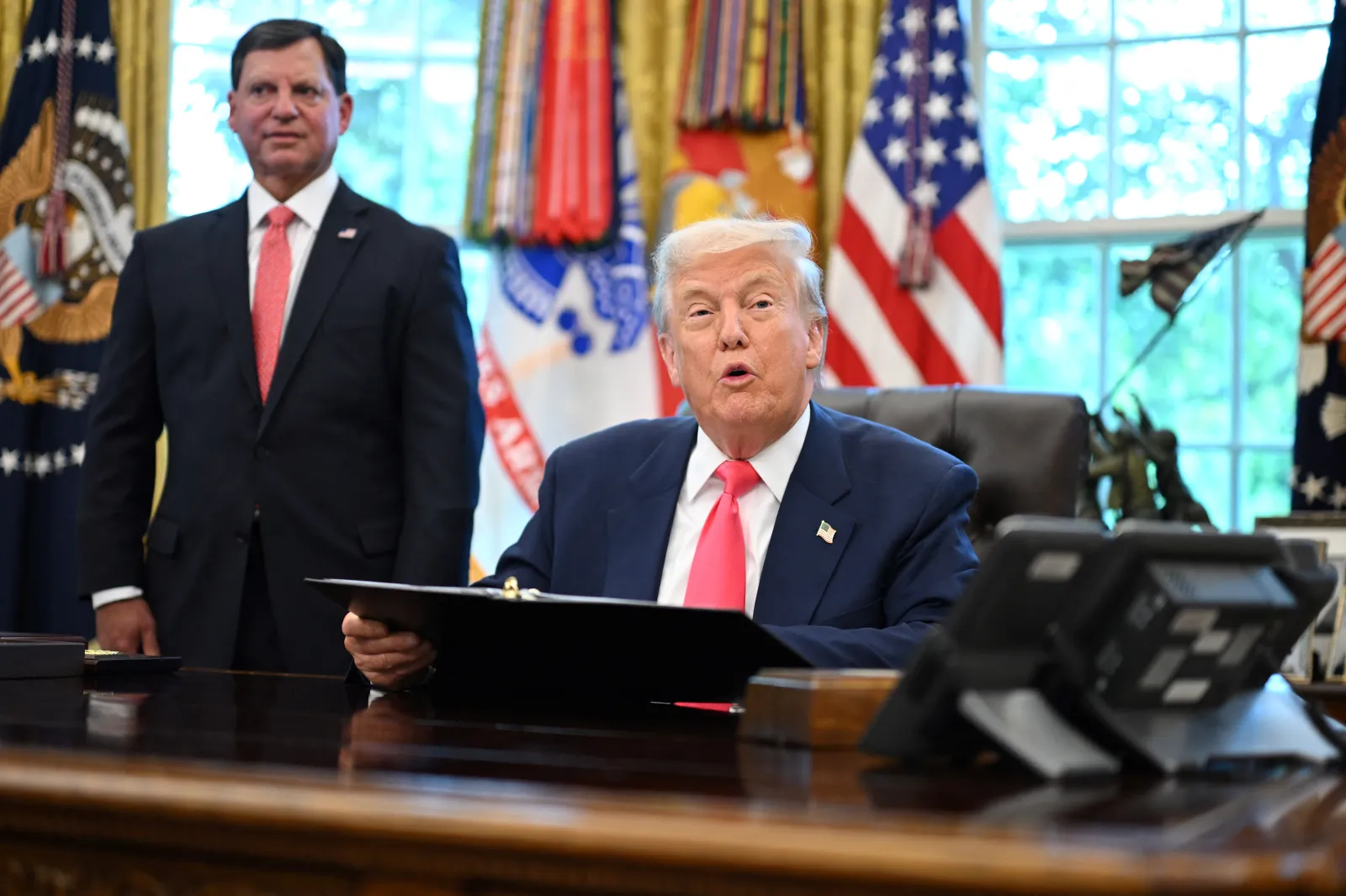President Donald Trump speaks as Social Security Administration Commissioner Frank Bisignano looks on prior at the White House in Washington, DC, on August 14,
