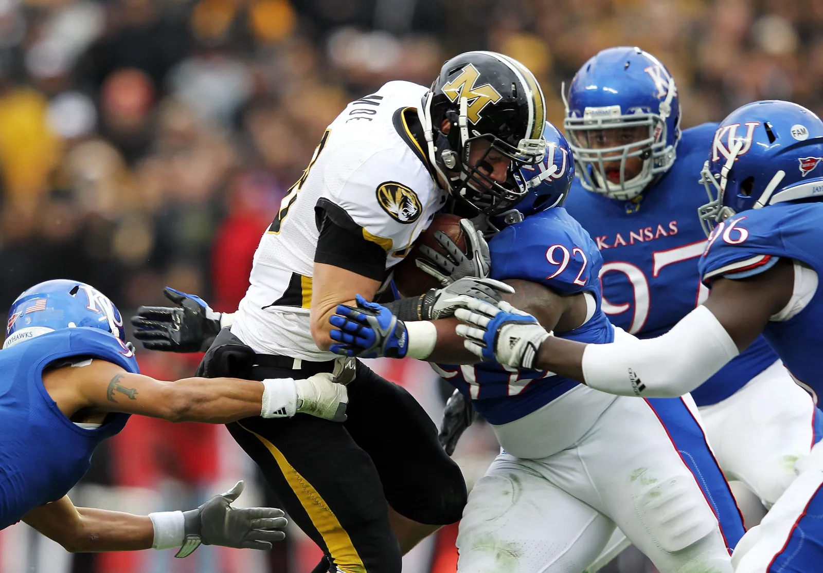 KANSAS CITY, MO - NOVEMBER 26: T.J. Moe #28 of the Missouri Tigers is stopped by Patrick Dorsey #92 of the Kansas Jayhawks during the game on November 26, 2011 