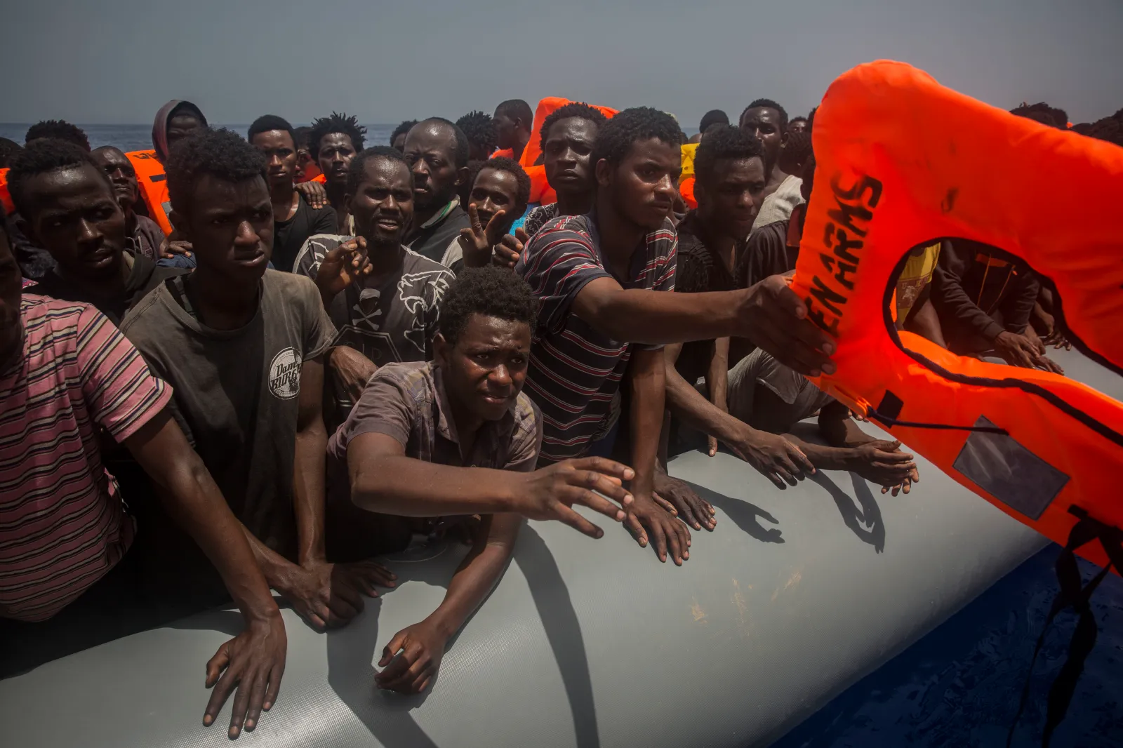 Migrants and refugees receive lifejackets from Spanish NGO Proactiva Open Arms workers, after being located sailing on an out of control rubber boat in the Mediterranean Sea, about 12 miles north of Sabratha, Libya, on Sunday, July 23, 2017. | AP Photo/Santi Palacios