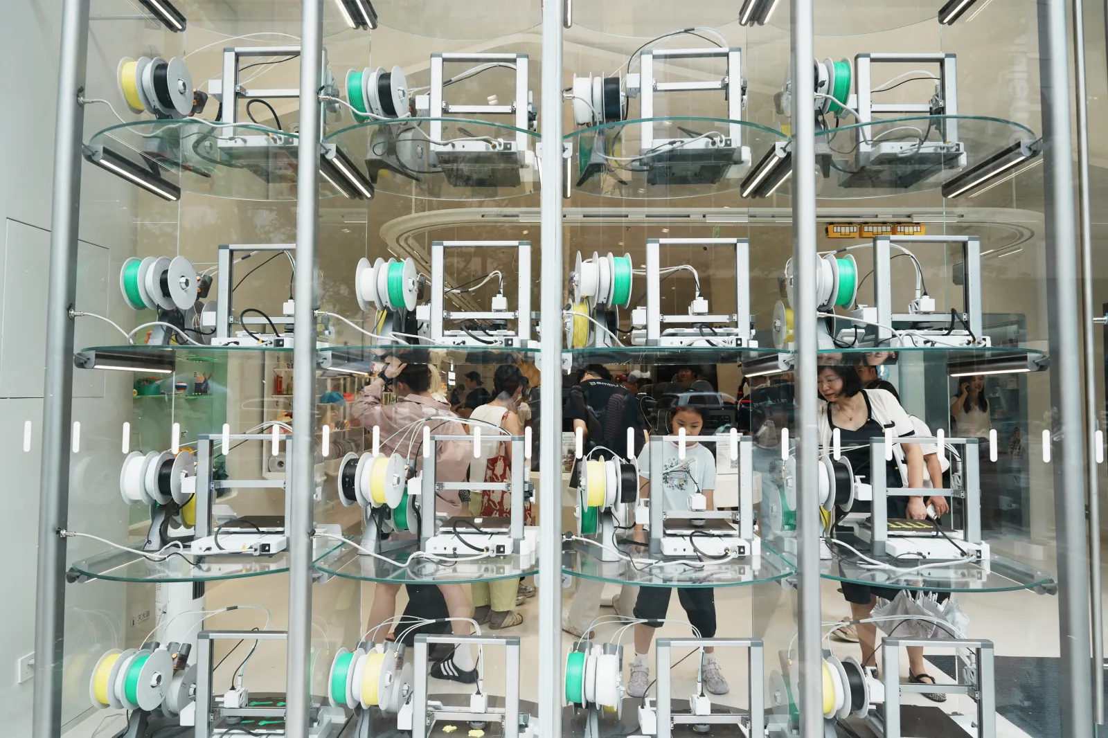 Customers watch the 3D printing process at the Bambu Lab flagship store on August 24, 2026, in Hangzhou in China's eastern Zhejiang province. The store features AI and 3D printing technologies.