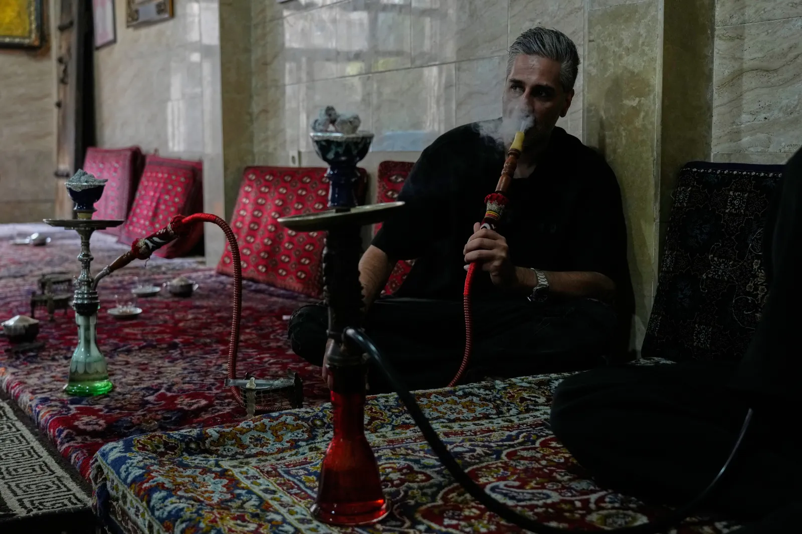 A man smokes a water pipe at a traditional restaurant in an old neighborhood in southern Tehran on October 1, 2026.