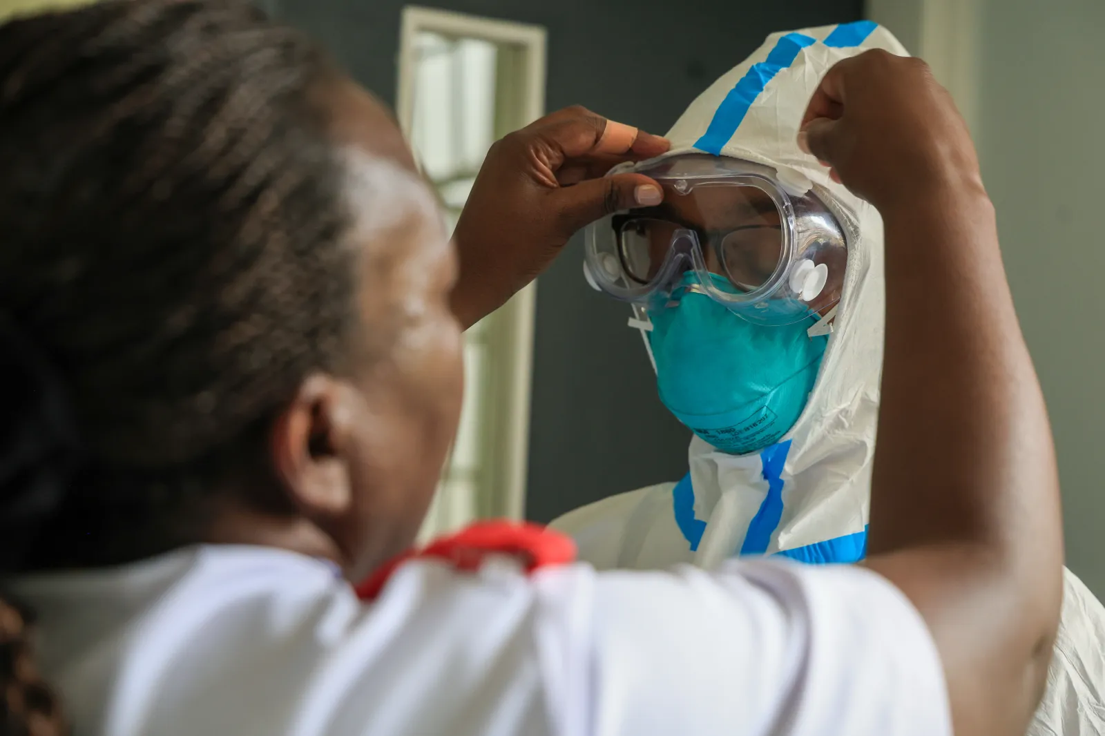 A health worker helps a colleague to put on personal protective equipment (PPE) in a room at an Ebola isolation facility at The Nairobi Hospital, Kenya, Wednesday, Oct. 7, 2026. | AP Photo/Andrew Kasuku