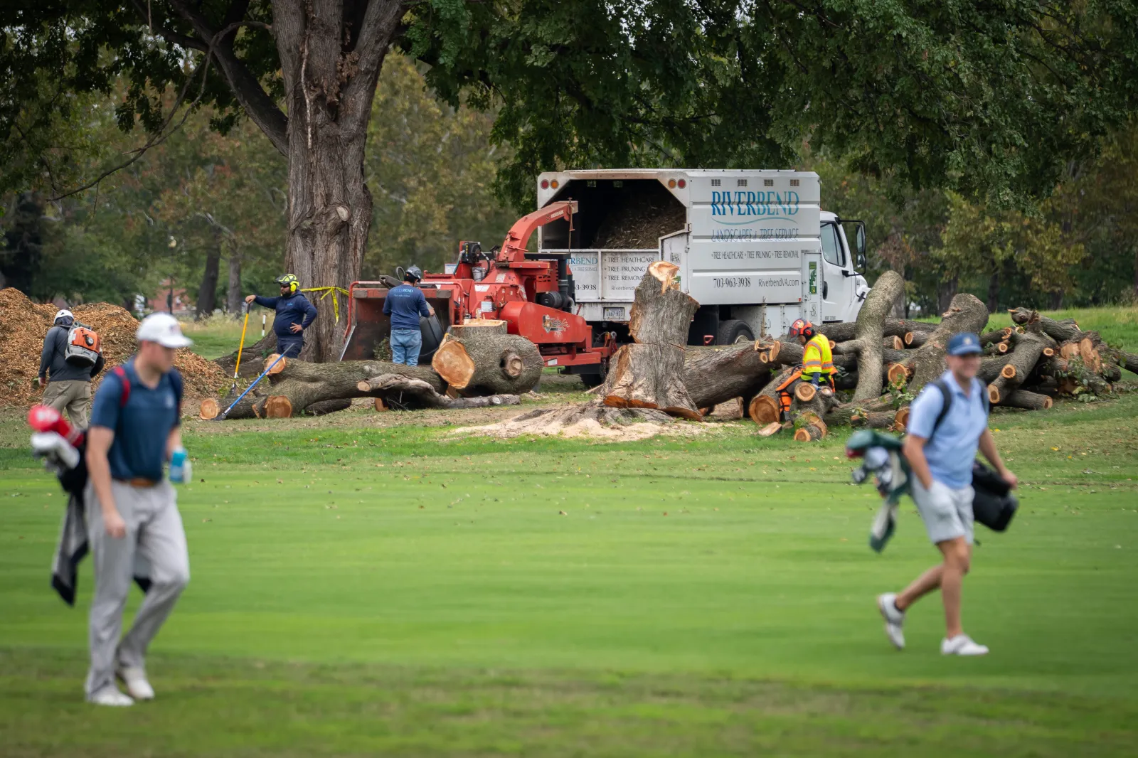 Golfers pass workers as the National Park Service begins cutting down trees at East Potomac Golf Links, Saturday, October 10, 2026, in Washington.