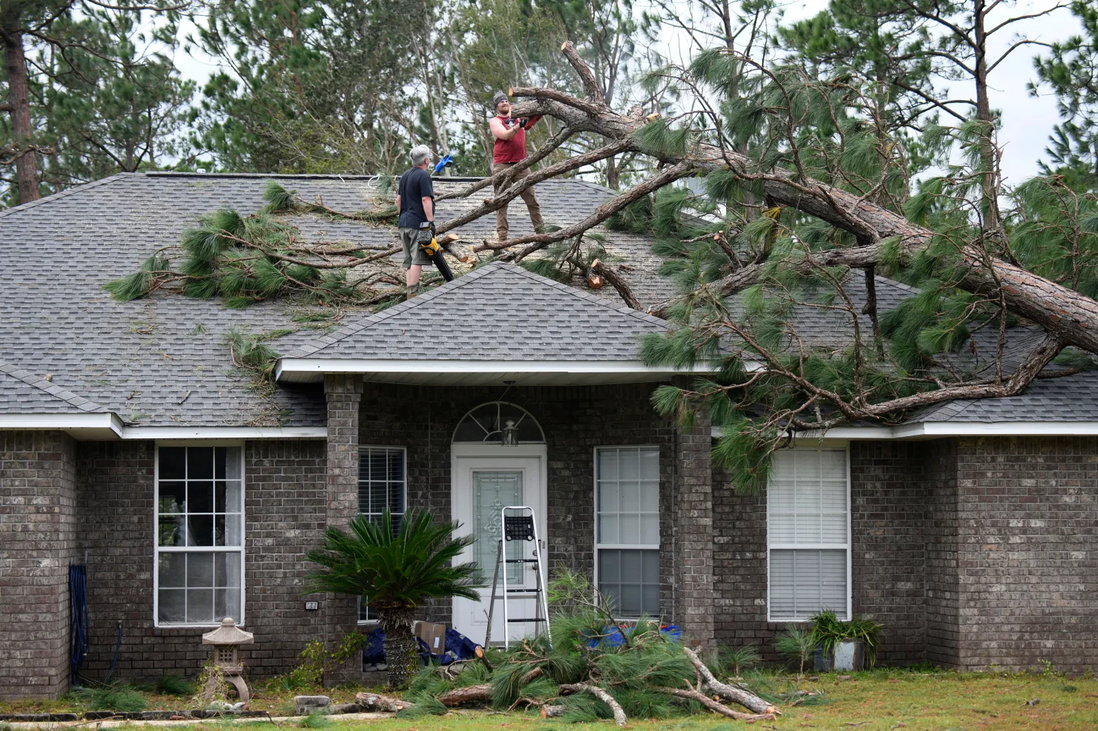 Jeff Lundy cuts up a pine tree that fell on his father-in-law's house during Isaias on Saturday, October 10, 2026, in Milton, Florida.