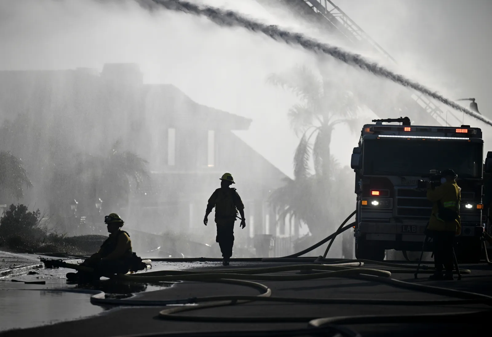 Firefighters put water on the roof of a house that burned during the Norte Fire on Friday, October 16, 2026, in San Juan Capistrano, California.