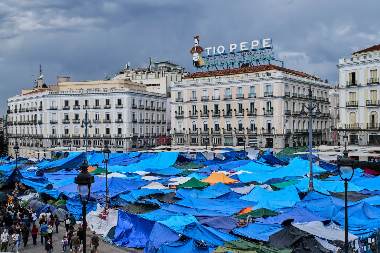 People walk among tents set up by protesters at the Puerta del Sol square demanding stronger laws to protect renters in Madrid on October 17.