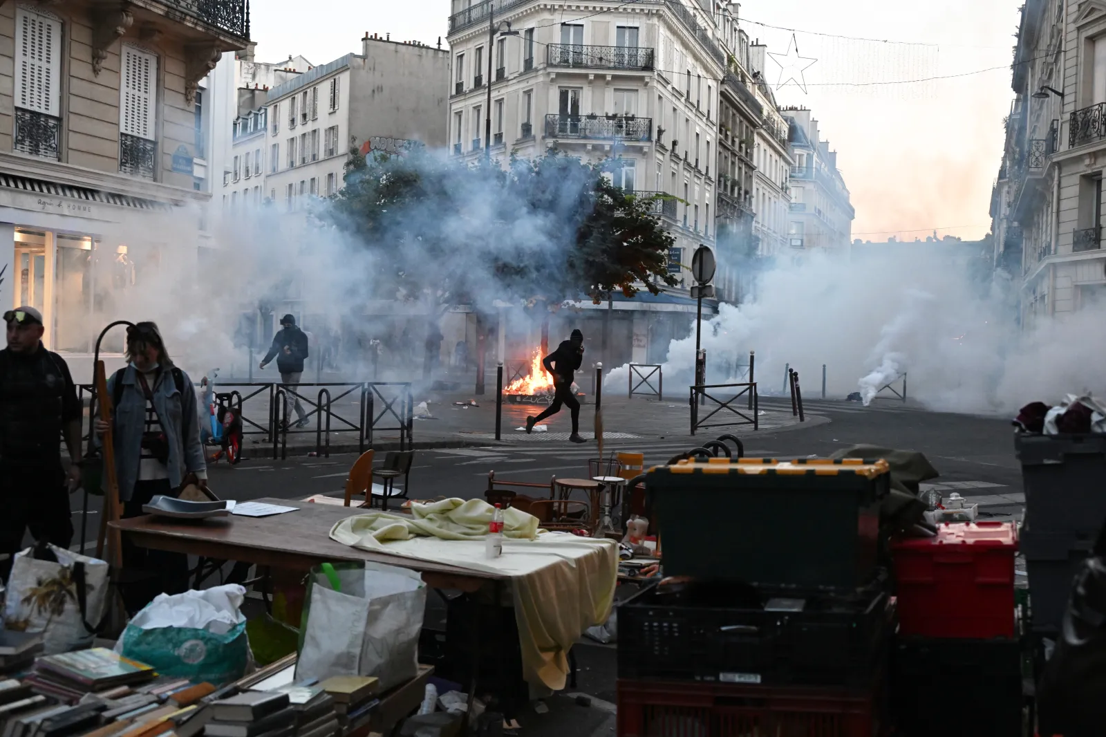 A protester runs through tear gas while a flea market is taking place during clashes between protesters and police officers in Paris, on October 18.