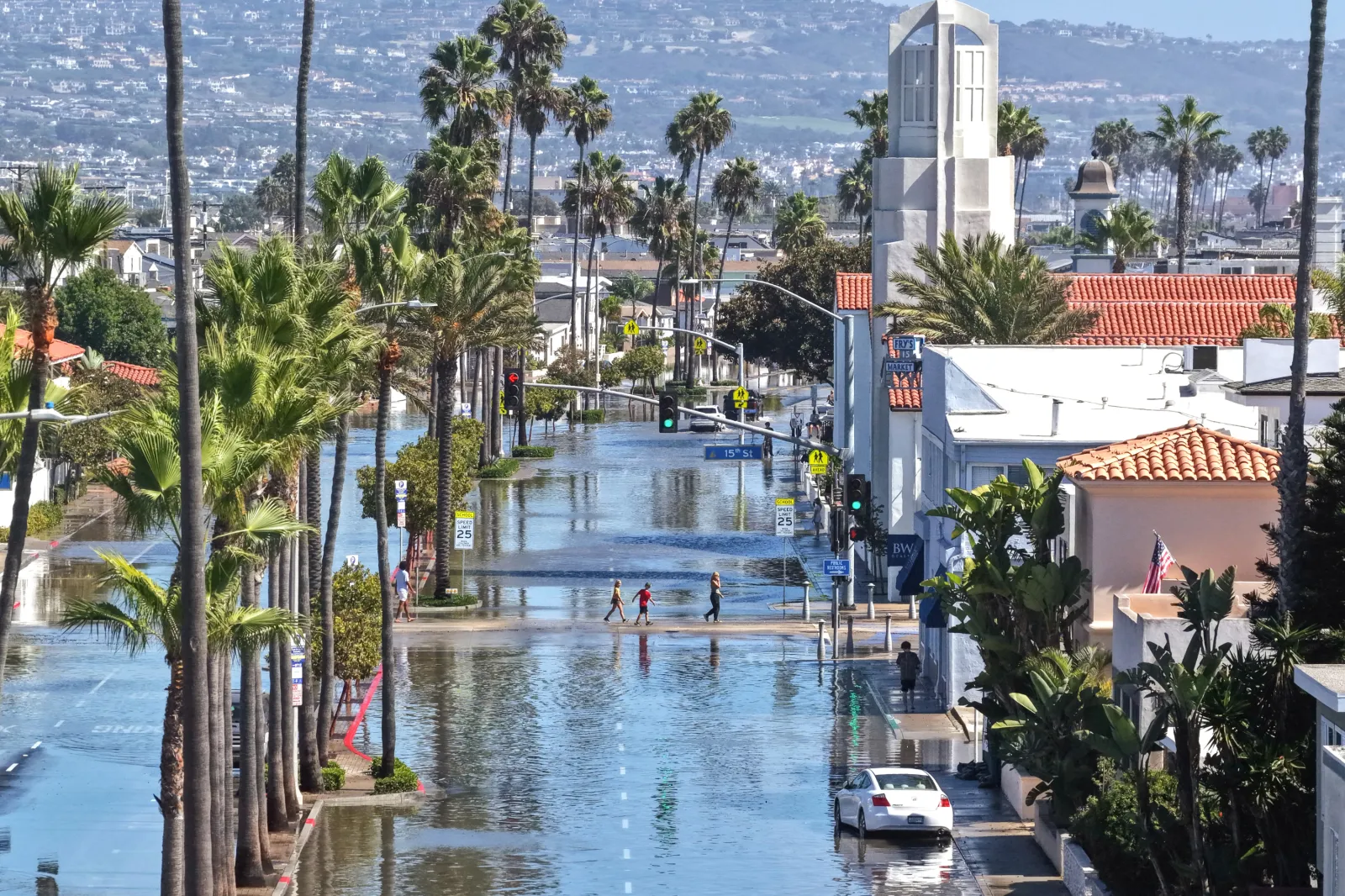 In an aerial view, people walk near coastal floodwaters amid strong waves and high tides generated by Tropical Storm Rachel on October 9, 2026, in Newport Beach, California.