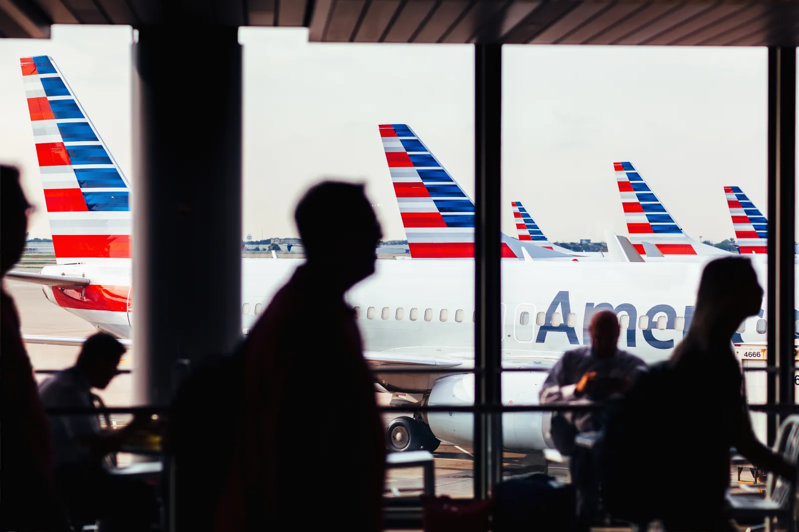 American Airlines fleet of airplanes with passengers at O'Hare Airport passing through corridor.