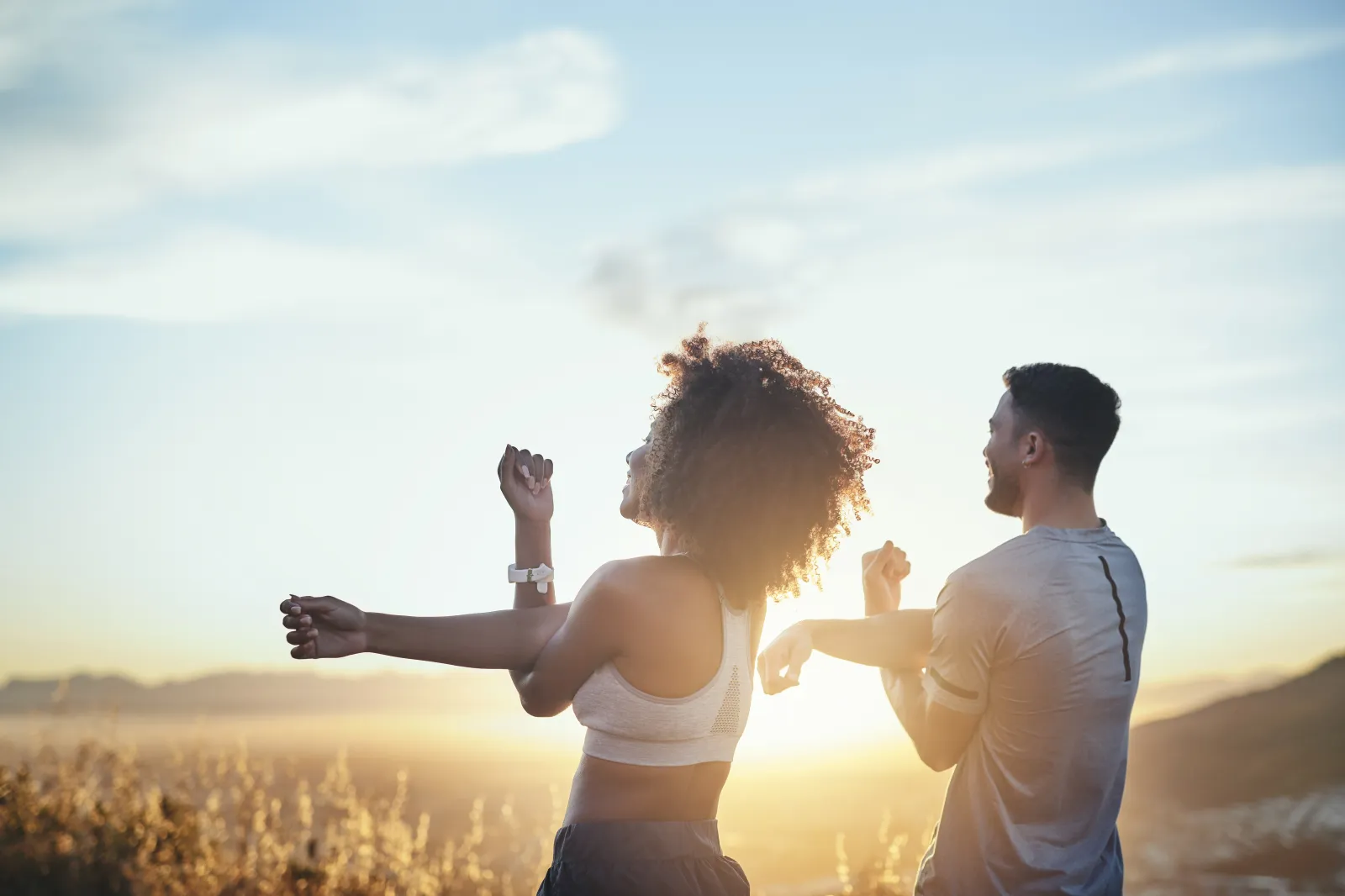 Stock image: A man and a woman stretching while out for a workout on a mountain road.