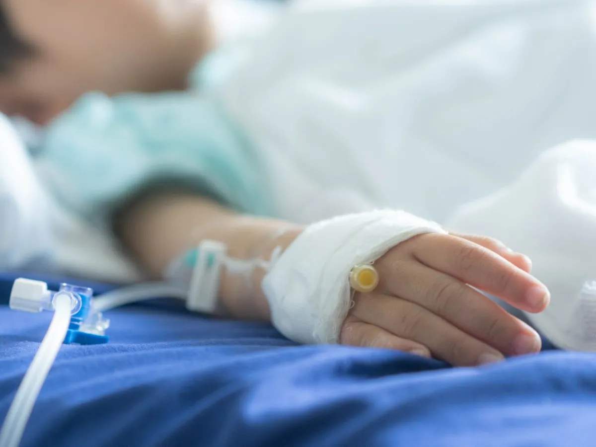 A child lies in a hospital bed with intravenous drip.