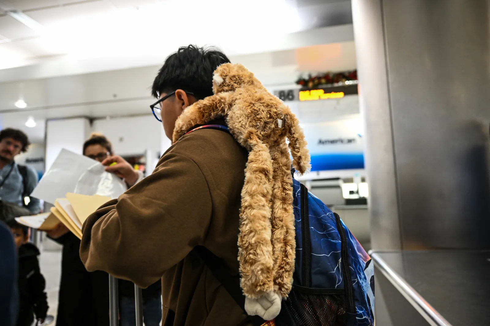 Alexis, a child of Guatemalan origin, holds his stuffed monkey as he waits inside Miami International Airport, along with six other children, to leave the United States and reunite with their recently deported parents in Guatemala, in Miami, Florida, on December 4, 2025.
