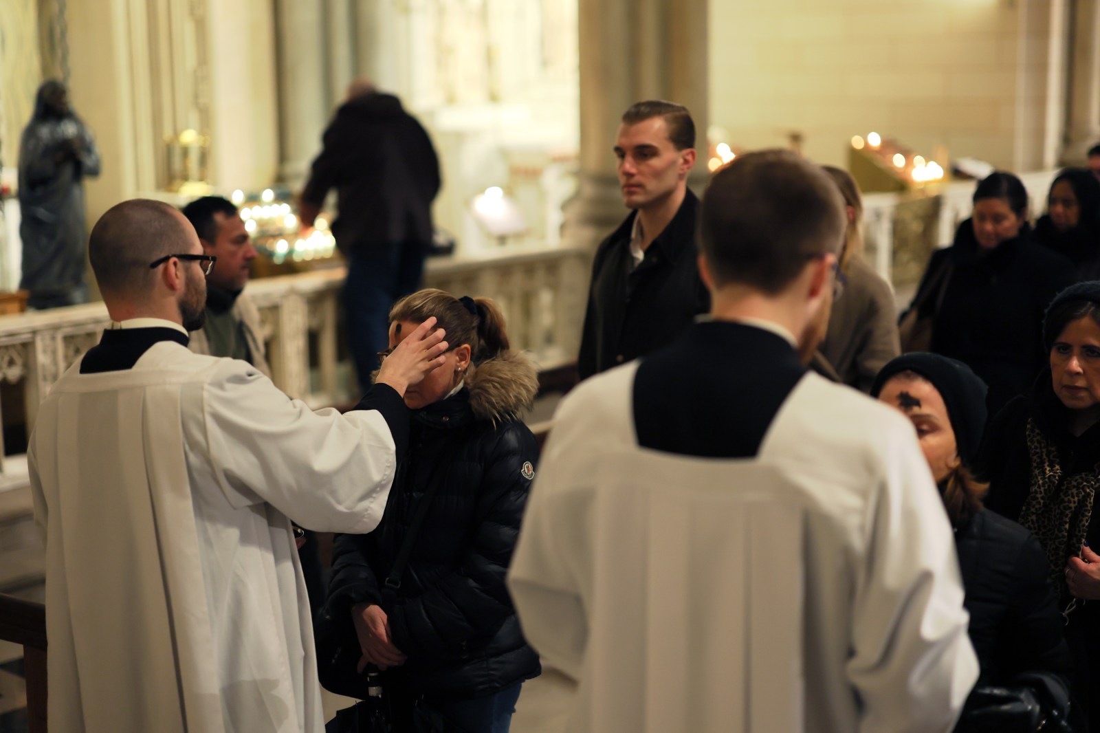 People receive the sign of the cross in ashes on their forehead by a priest at St. Patrick