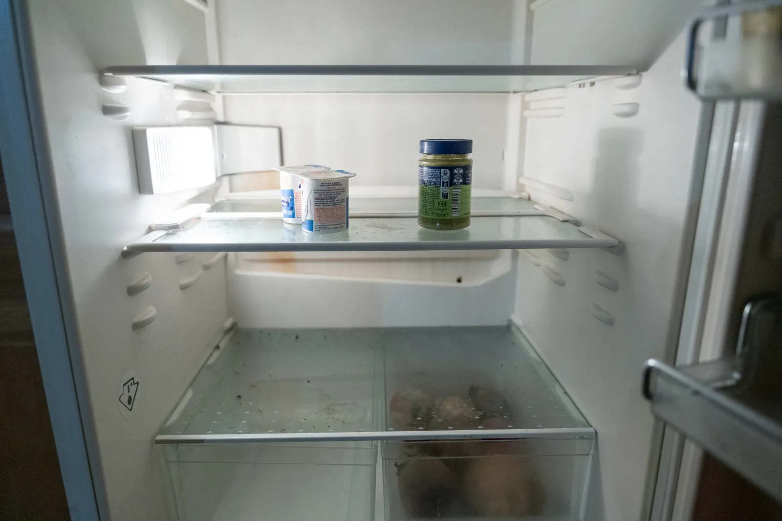 An empty fridge containing two yogurts, a jar of pesto, and some winter vegetables illustrates the poverty and difficulty faced by a portion of the population in feeding themselves adequately in Lyon, France on February 23, 2026. | Photo by Antoine Boureau / Hans Lucas / AFP via Getty Images