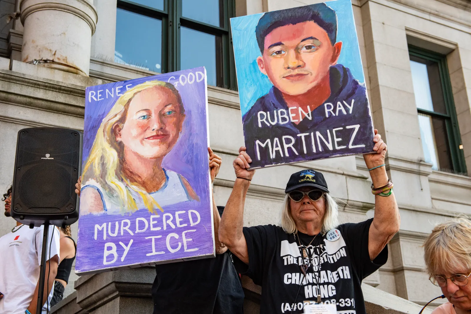 Demonstrators hold paintings to remember those who have been killed during federal immigration enforcement operations, at a candlelight vigil at city hall in Providence, Rhode Island, on July 25.