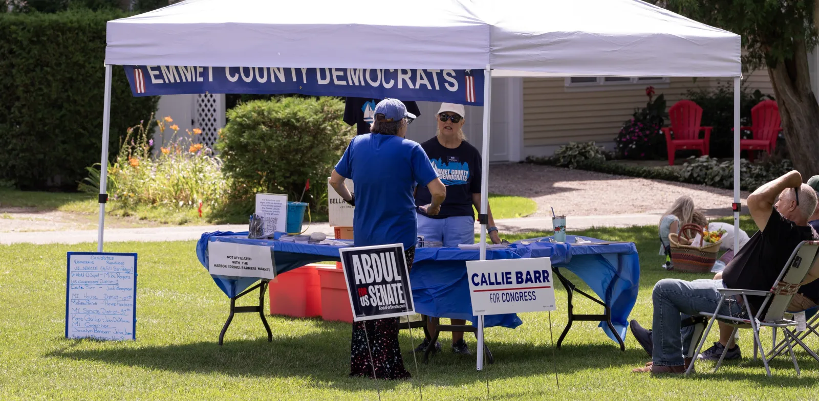 Emmet County Democrats pop-up tent in Zorn Park, Harbor Springs, Michigan to support their 2026 general election candidates. Yard signs can be seen for Abdul El-Sayed for United States Senate and Callie Barr for Michigan's 1st Congressional District.