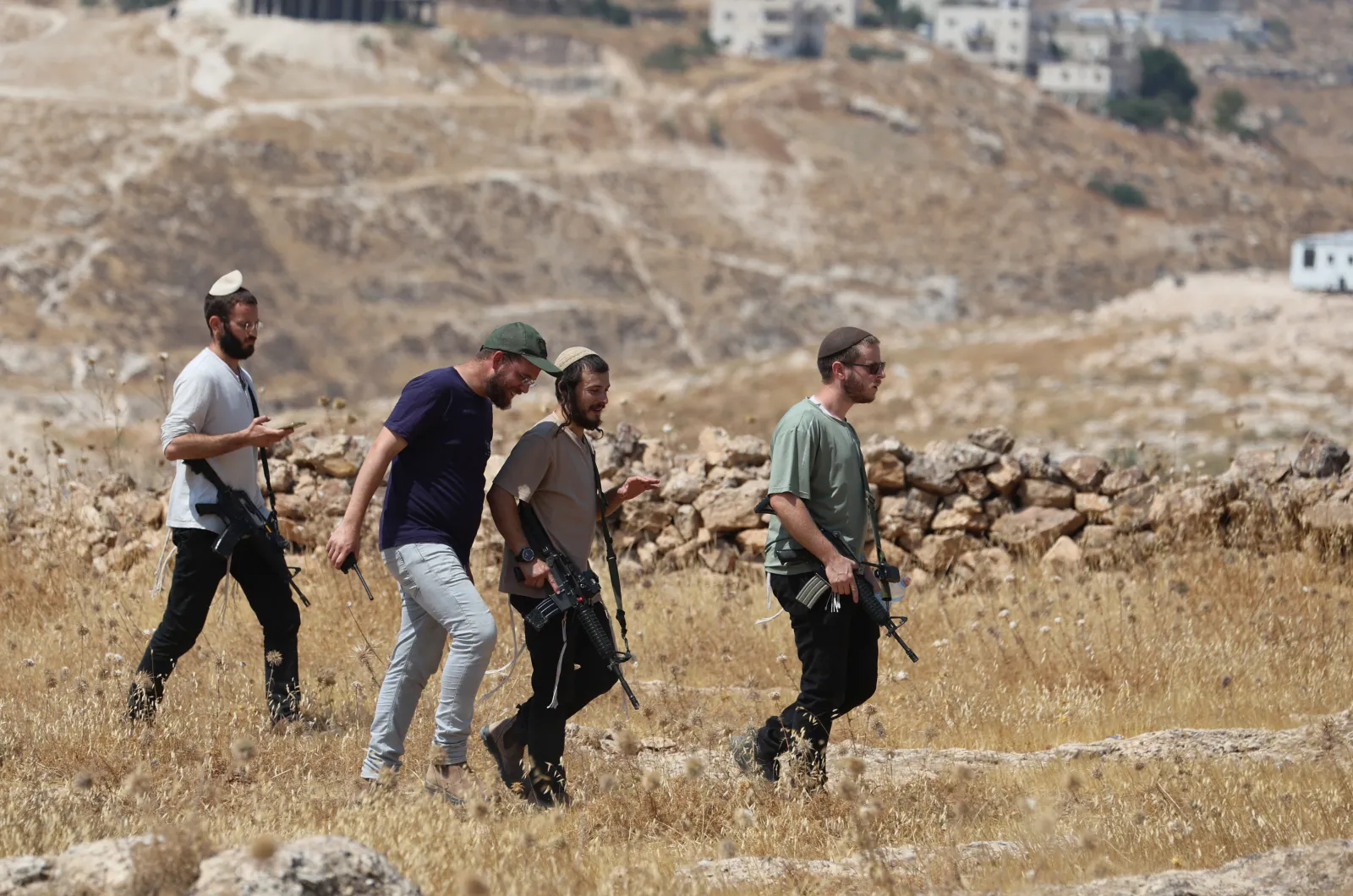 Armed men walk across open ground near the activists in Beit Sahour, east of Bethlehem in the occupied West Bank, on August 14, 2026.