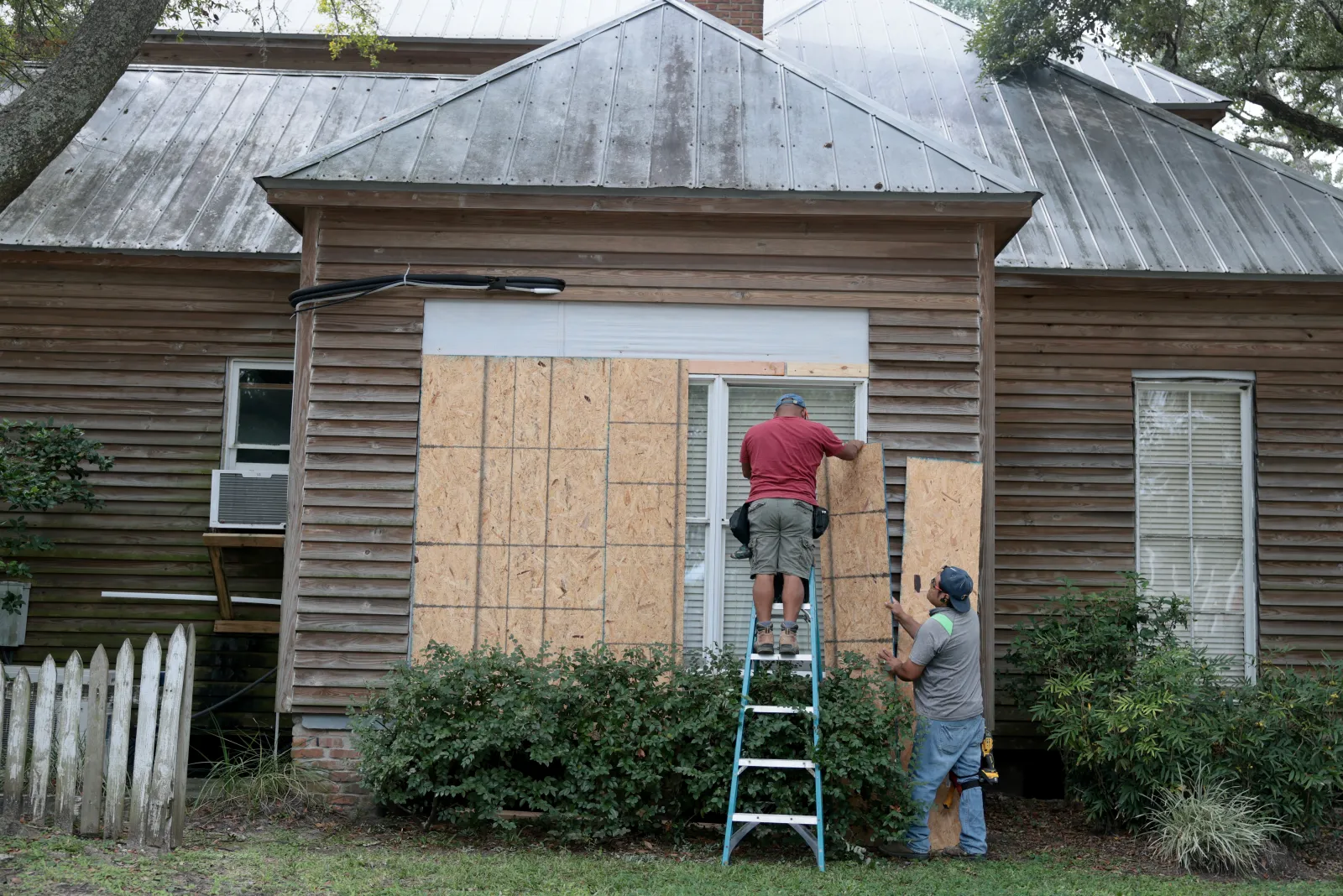 Aaron Chi and Wilner Garcia put plywood over home windows before the possible arrival of Hurricane Isaias, October 8, 2026, Pensacola.