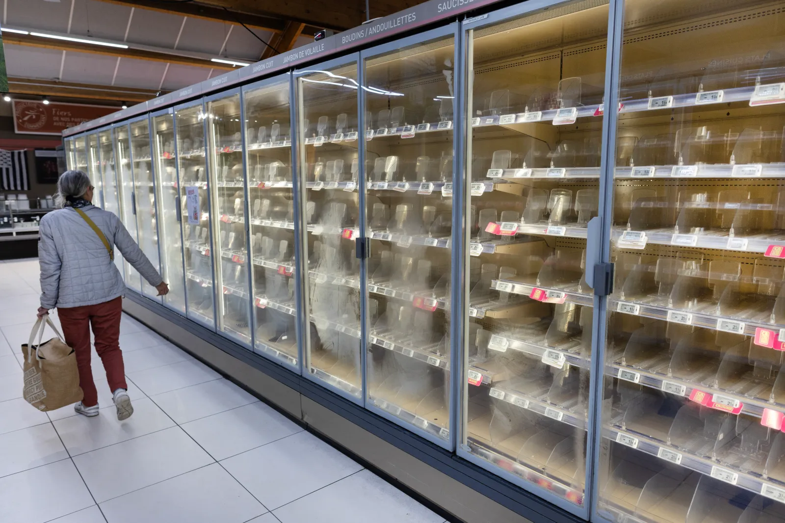 A woman walks past empty fresh-food refrigerators at an Intermarché supermarket following a cyberattack affecting the French supermarket chains Intermarché and Cooperative U that caused their refrigerators to defrost in Névez, western France, on October 12, 2026. | Photo by Fred TANNEAU / AFP via Getty Images