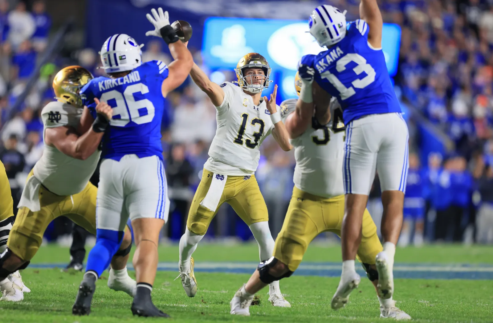 CJ Carr #13 of the Notre Dame Fighting Irish throws a pass under pressure from Justin Kirkland #96 and Tausili Akana #13 of the Brigham Young Cougars