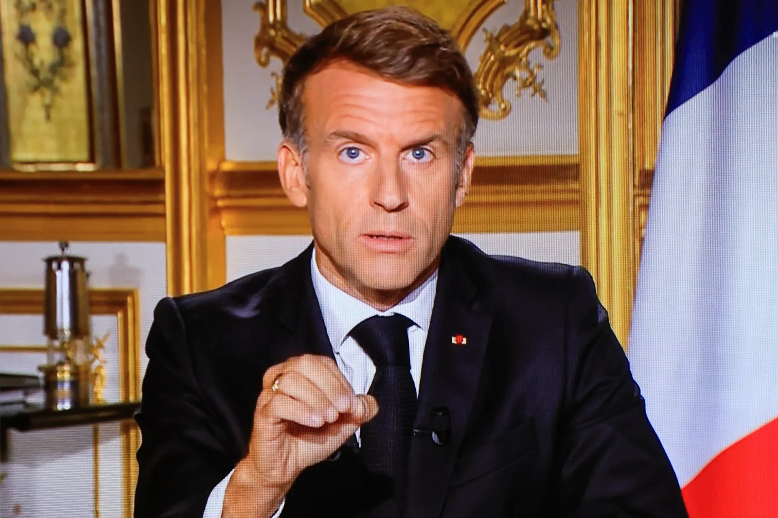 This image shows a television monitor broadcasting French President Emmanuel Macron giving a speech from the Elysee Palace in Paris on October 18, 2026, a day after nationwide riots and looting.