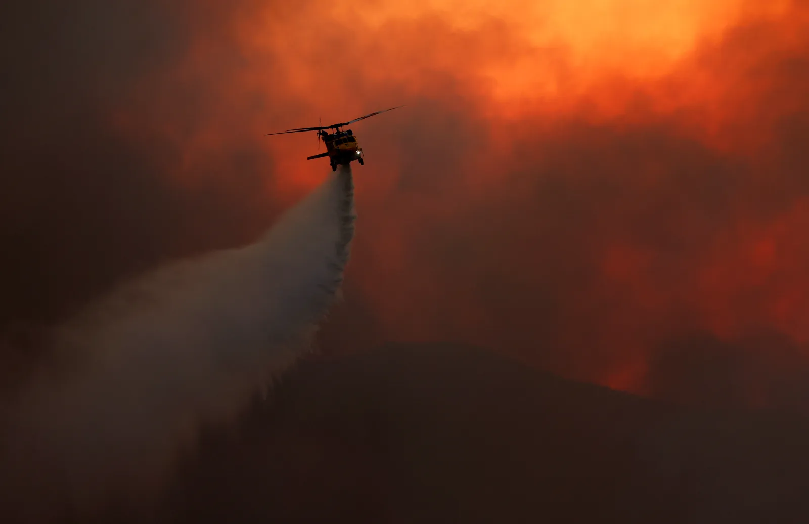 A firefighting helicopter douses the Bryson Fire on Thursday in Malibu, California. (Photo by Justin Sullivan/Getty Images)