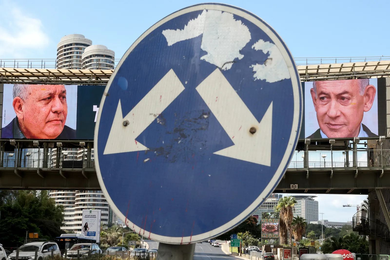 A road sign stands in front of a large billboard featuring Israel's Prime Minister Benjamin Netanyahu, right, of the Likud party, and former military chief and leader of the centrist Yashar party, Gadi Eisenkot, left, in Ramat Gan on October 20, 2026.