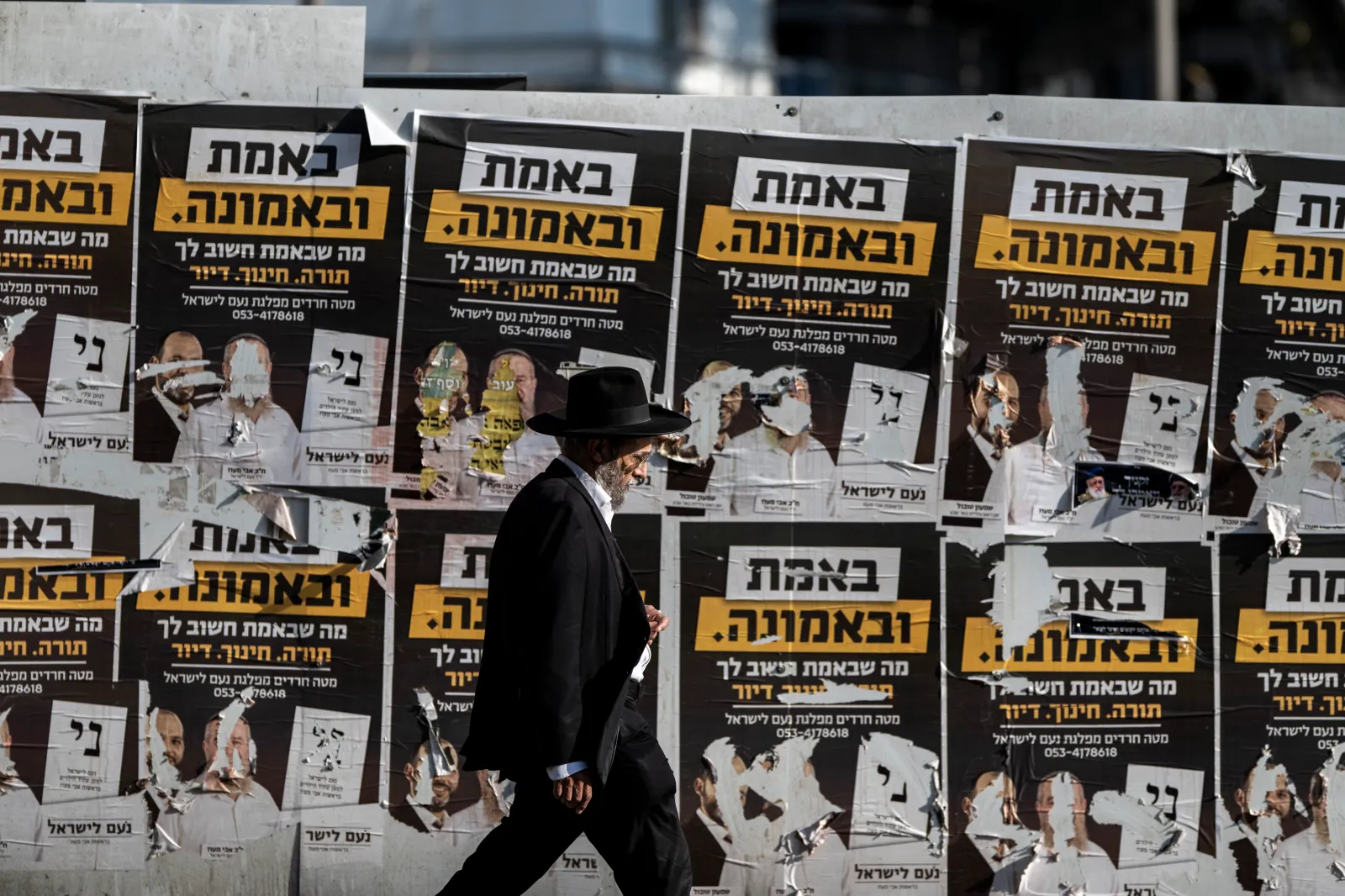 An ultra-Orthodox Jewish man walks past electoral posters on a wall along a street in Jerusalem on October 21, 2026, ahead of Israel's legislative election.