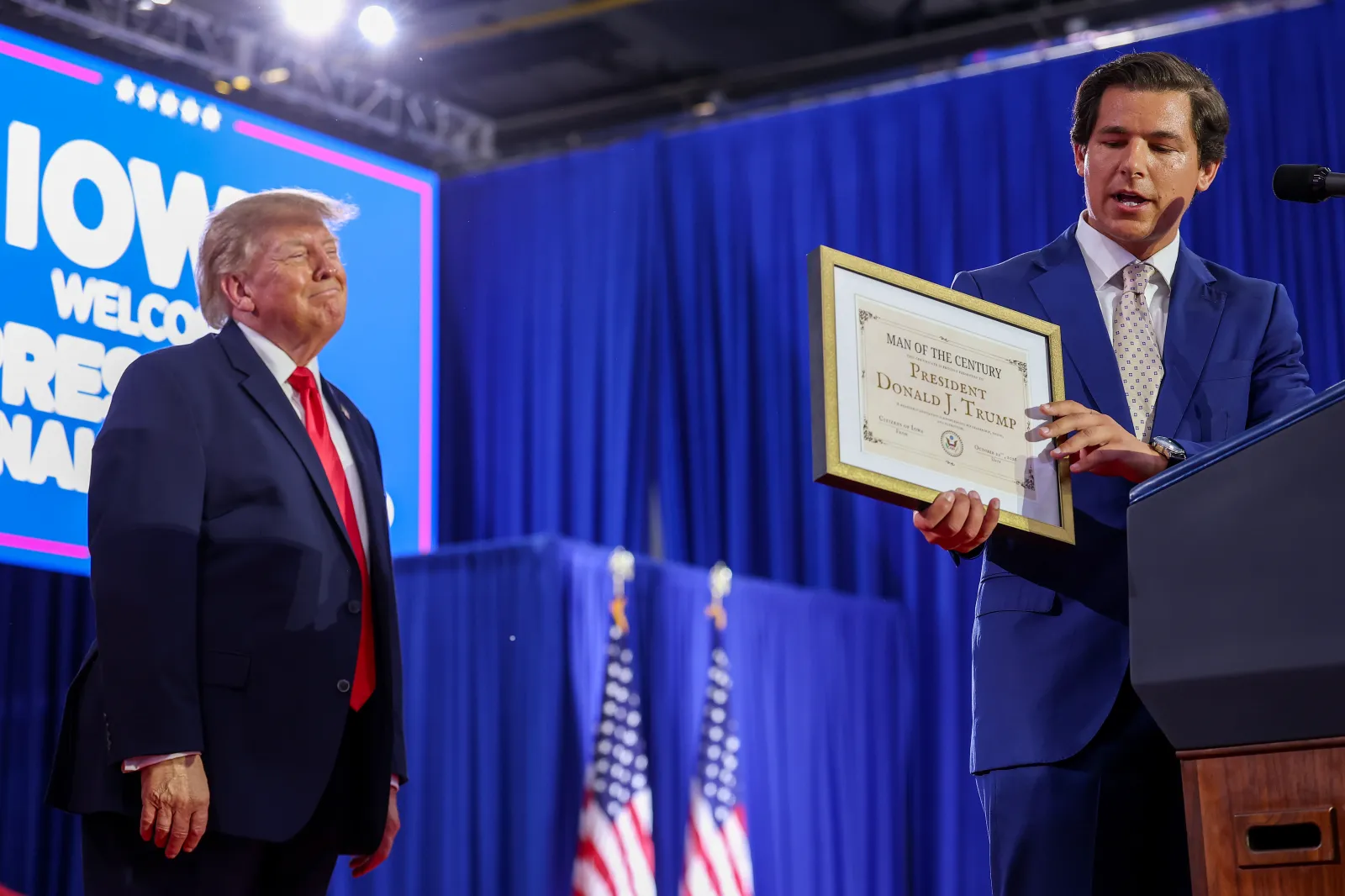 Iowa Republican House candidate Joe Mitchell (R) presents U.S. President Donald Trump (L) with a self-made "Man of the Century Award" during a rally at Sioux Gateway Airport on October 22, 2026 in Sioux City, Iowa. President Trump traveled to Iowa to rally support for local Republican candidates ahead of the upcoming midterm elections. (Photo by Anna Moneymaker/Getty Images)