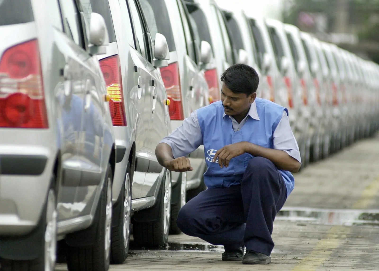 An Indian emloyee of Hyundai Motor India checks car tyres in Madras, 12 August 2003.