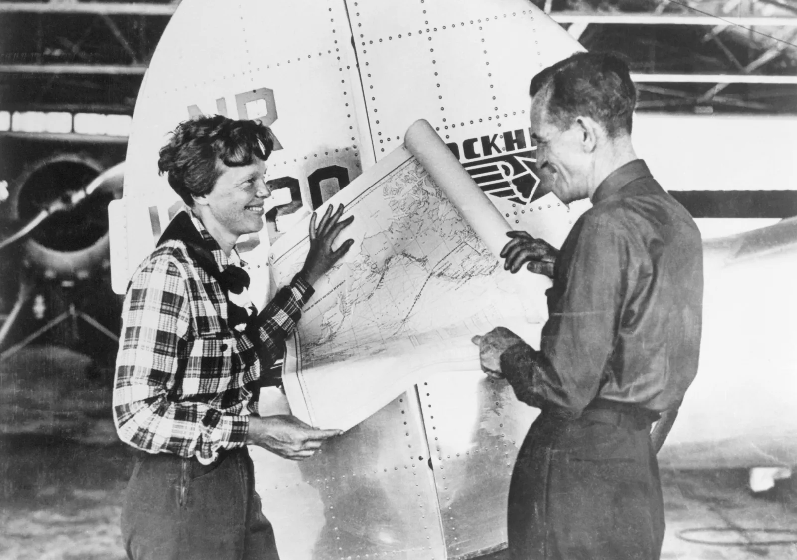Amelia Earhart and her navigator, Fred Noonan, with a map of the Pacific that shows the planned route of their last flight.